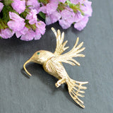 Yellow gold flying bird brooch. A rich textured finish to the body and wings of the bird, with an emerald eye. 