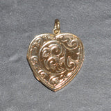 Gold heart-shaped pendant with intricate designs on a gray background