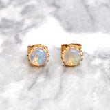 Opal stud earrings with gold rims on a marble background