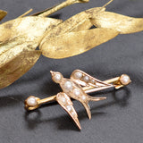 Gold bird-shaped brooch with pearl accents on a dark background