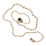 A single row of graduated cultured pearls with a gold clasp featuring pearls and a garnet.