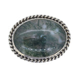 An oval moss agate within a silver brooch, edged with a silver rope. 