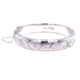 Vintage silver bangle with leaf patterns, featuring a safety chain.